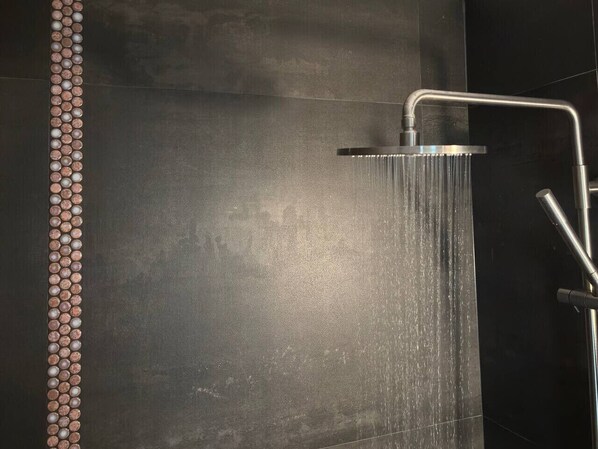 A shower with a modern design, featuring a vertical strip of decorative elements on the wall.