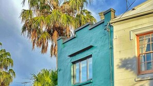 A two-story building with a teal facade and a red door.