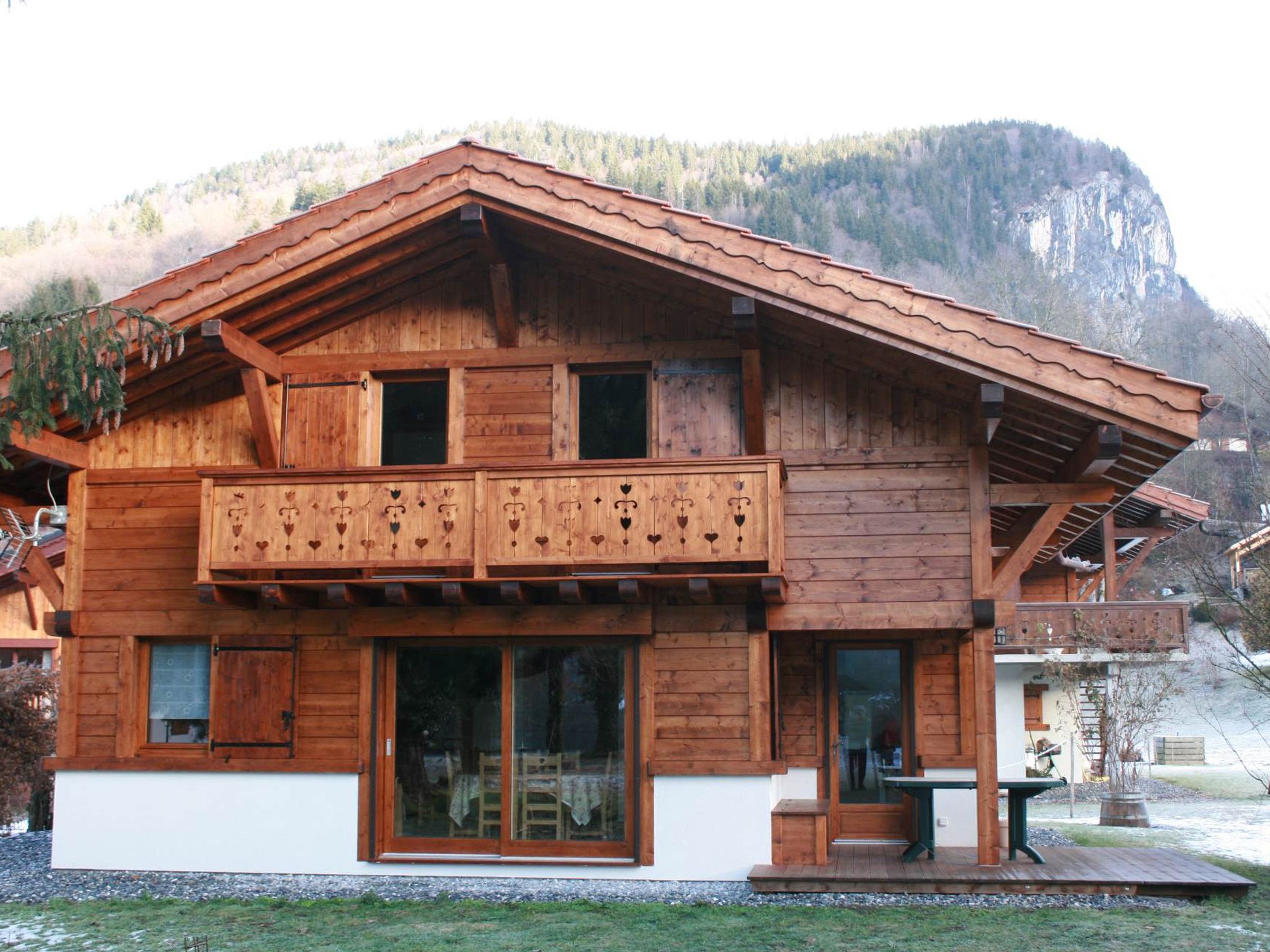 Un chalet de madera con balcón, ventanas amplias y vistas a la montaña.