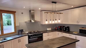 A modern kitchen with white cabinets, a stainless steel stove, and a large island. - Large family home with private pool, pets allowed (Isigny-le-Buat)