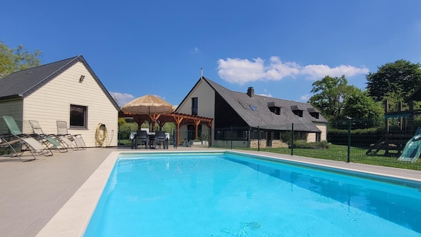 A swimming pool with lounge chairs and a covered patio area. - Large family home with private pool, pets allowed (Isigny-le-Buat)