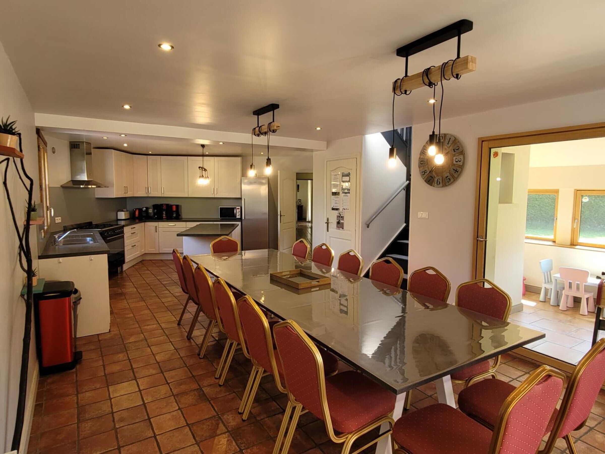 A modern kitchen with a central island, white cabinets, and a dining area with red chairs.