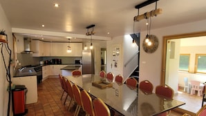 A modern kitchen with a central island, white cabinets, and a dining area with red chairs. - Large family home with private pool, pets allowed (Isigny-le-Buat)
