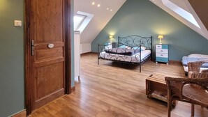 A bedroom with a sloped ceiling, a wooden door, a bed with a metal frame, a nightstand, a chair, and a small table. - Large family home with private pool, pets allowed (Isigny-le-Buat)