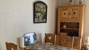 A cozy room with a wooden dining table, chairs, and a cabinet with heart-shaped cutouts.