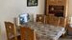 A dining area with a table and chairs, a wooden cabinet, and a framed picture on the wall.