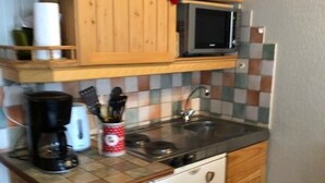 A small kitchen with a microwave, coffee maker, and a refrigerator.