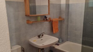 Een badkamer met een wastafel, spiegel en douche.