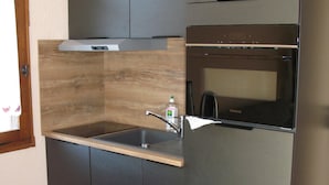 A modern kitchen with a stainless steel sink, a built-in oven, and a microwave.