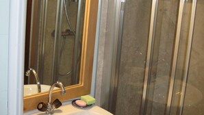 A bathroom with a glass shower enclosure, a sink with a mirror, and a soap dish.