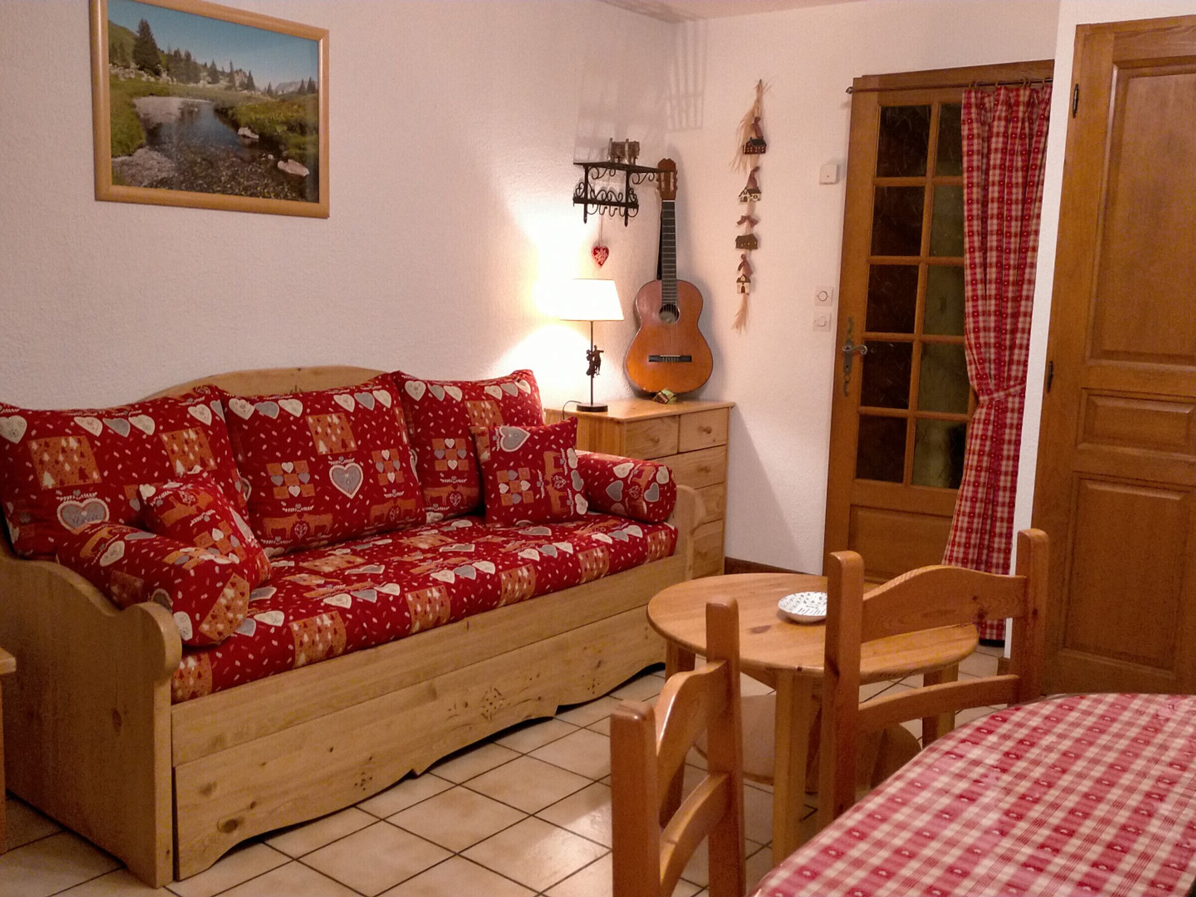 A cozy room with a wooden sofa, a small table, and a guitar.
