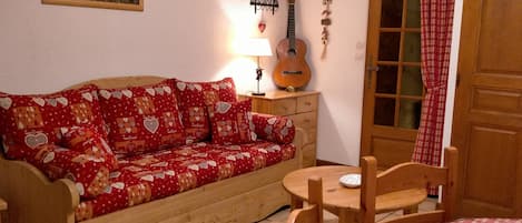 A cozy room with a wooden sofa, a small table, and a guitar.