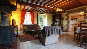 A cozy living room with a fireplace, a sofa, a coffee table, and a dining area with a table and chairs.