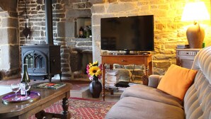 A cozy living room with a stone fireplace, a television, and a comfortable sofa.