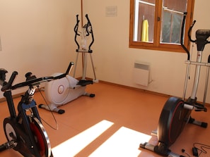 Une pièce équipée d’un vélo d’appartement, d’un vélo stationnaire et d’un tapis de course.