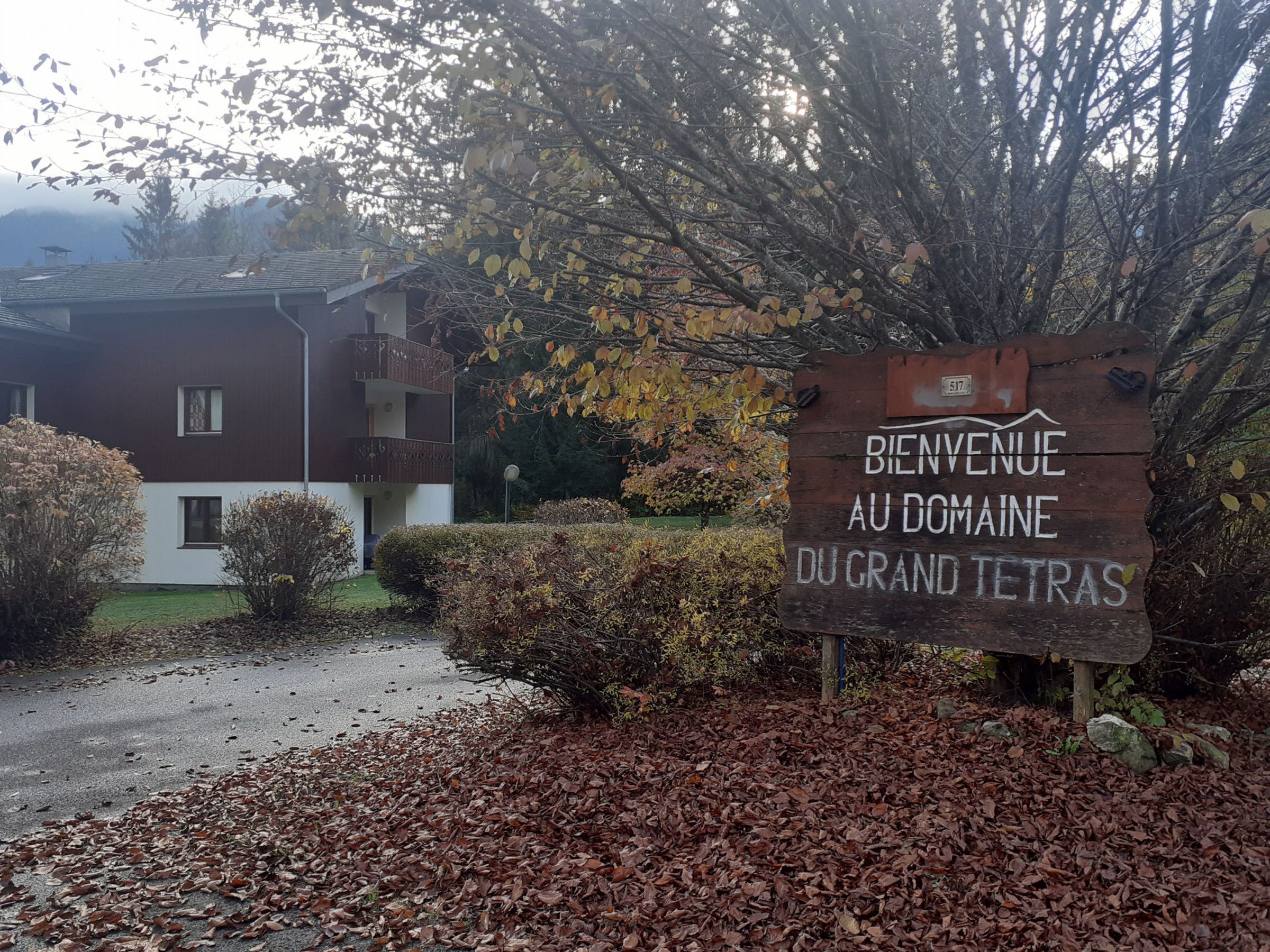 A wooden sign with 'BIENVENUE AU DOMAINE DU GRAND TETRAS' text, indicating a welcome sign at a property.