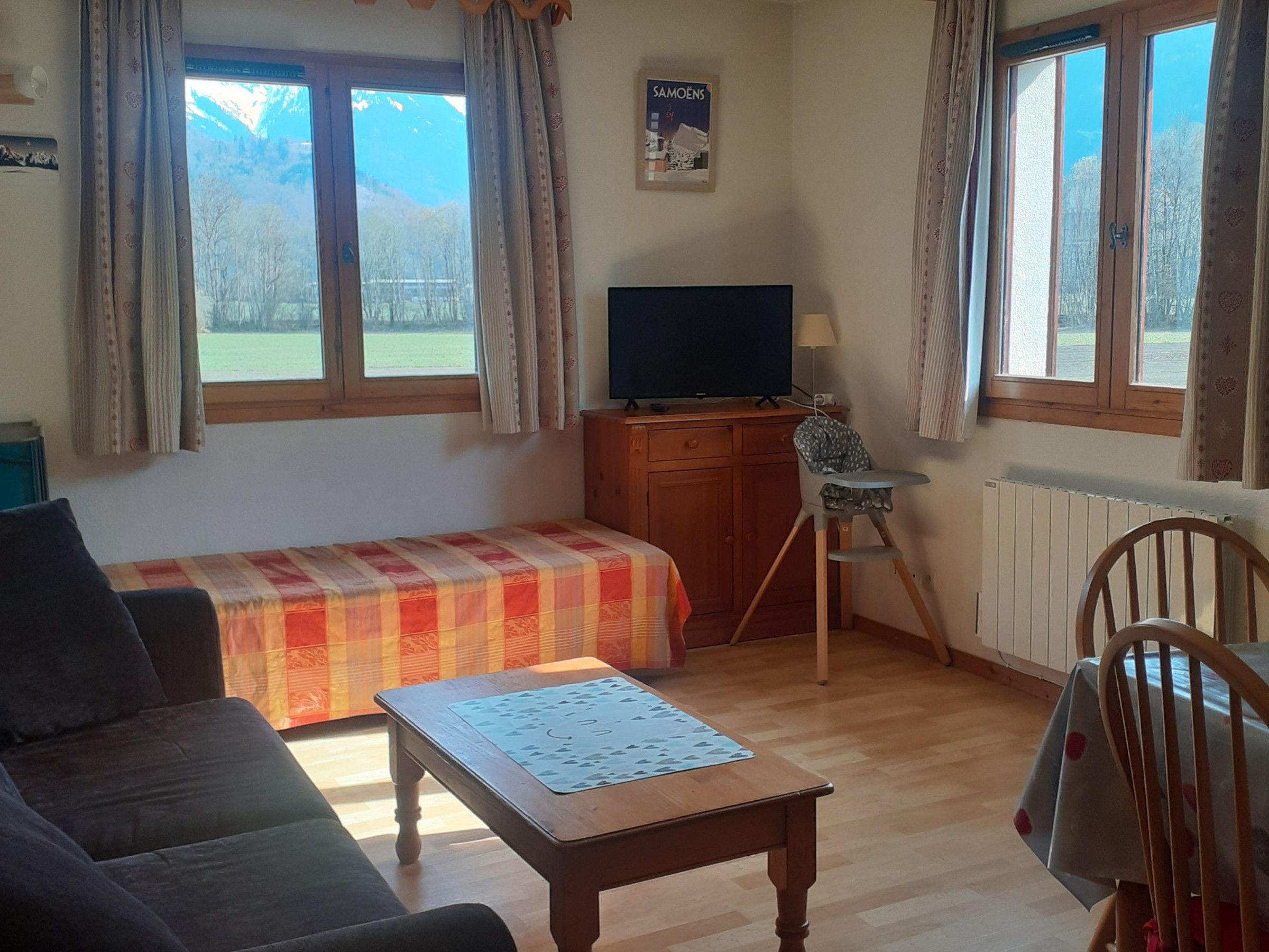 A room with a bed, a television, a desk, a chair, and a table.