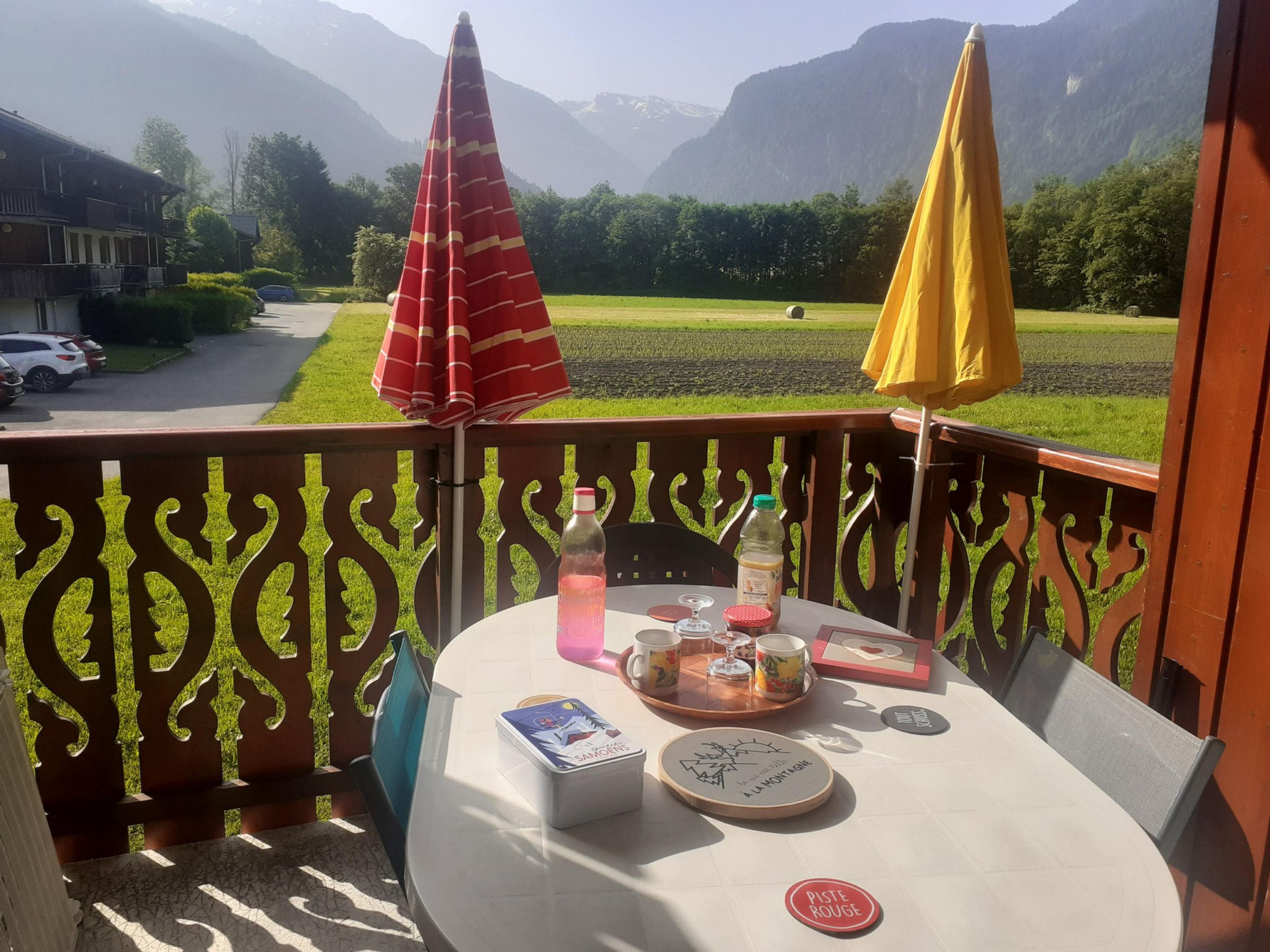 A balcony with a table set for two, featuring a bottle, glasses, and a menu.