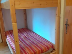 A bunk bed with a striped mattress, wooden frame, and a door with a handle.