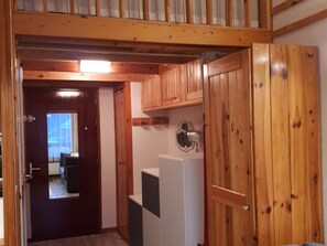 A wooden interior with a door leading to a room, a white appliance, and a ceiling fan. - Cozy studio for 2 in Samoëns (Samoëns)