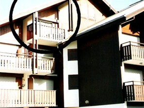 A multi-story building with balconies, a garage door, and a window.