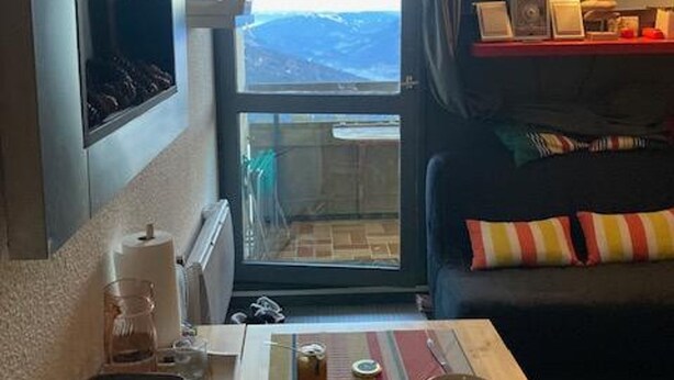 A hotel room with a bed, a small table with a lamp, a window with a view, and a shelf with items. - Cozy studio for 5 people in Samoëns (Samoëns)