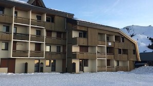 A multi-story hotel with balconies, a ski slope in the background, and a snowy landscape. - Cozy studio for 5 people in Samoëns (Samoëns)