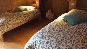 A cozy cabin with two wooden bunk beds, each with patterned bedding and a small stuffed toy.