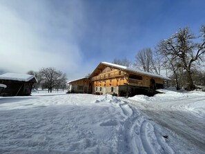Un chalet en bois doté d’un balcon, entouré d’un paysage enneigé et d’arbres.