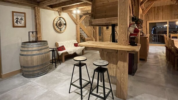 A rustic interior with wooden beams, a bar area, a sofa, and a clock on the wall. - Spacious chalet in Samoëns, 6 bedrooms, perfect for 14 people with Wifi (Samoëns)
