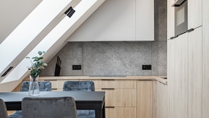 Une cuisine moderne dotée d’une verrière, de meubles en bois et d’un coin repas avec des chaises.