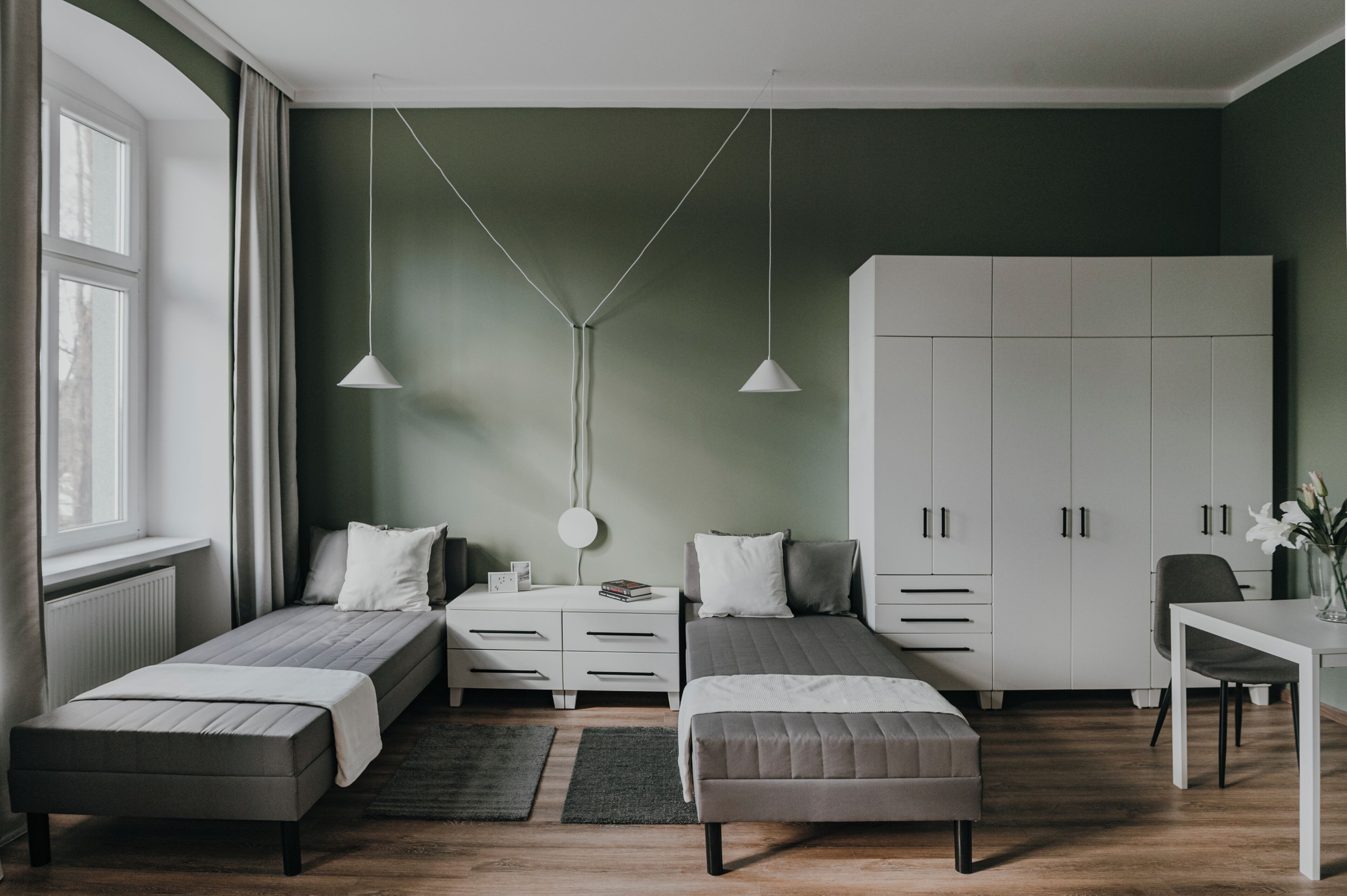 Quarto moderno com duas camas, uma escrivaninha e um guarda-roupa.
