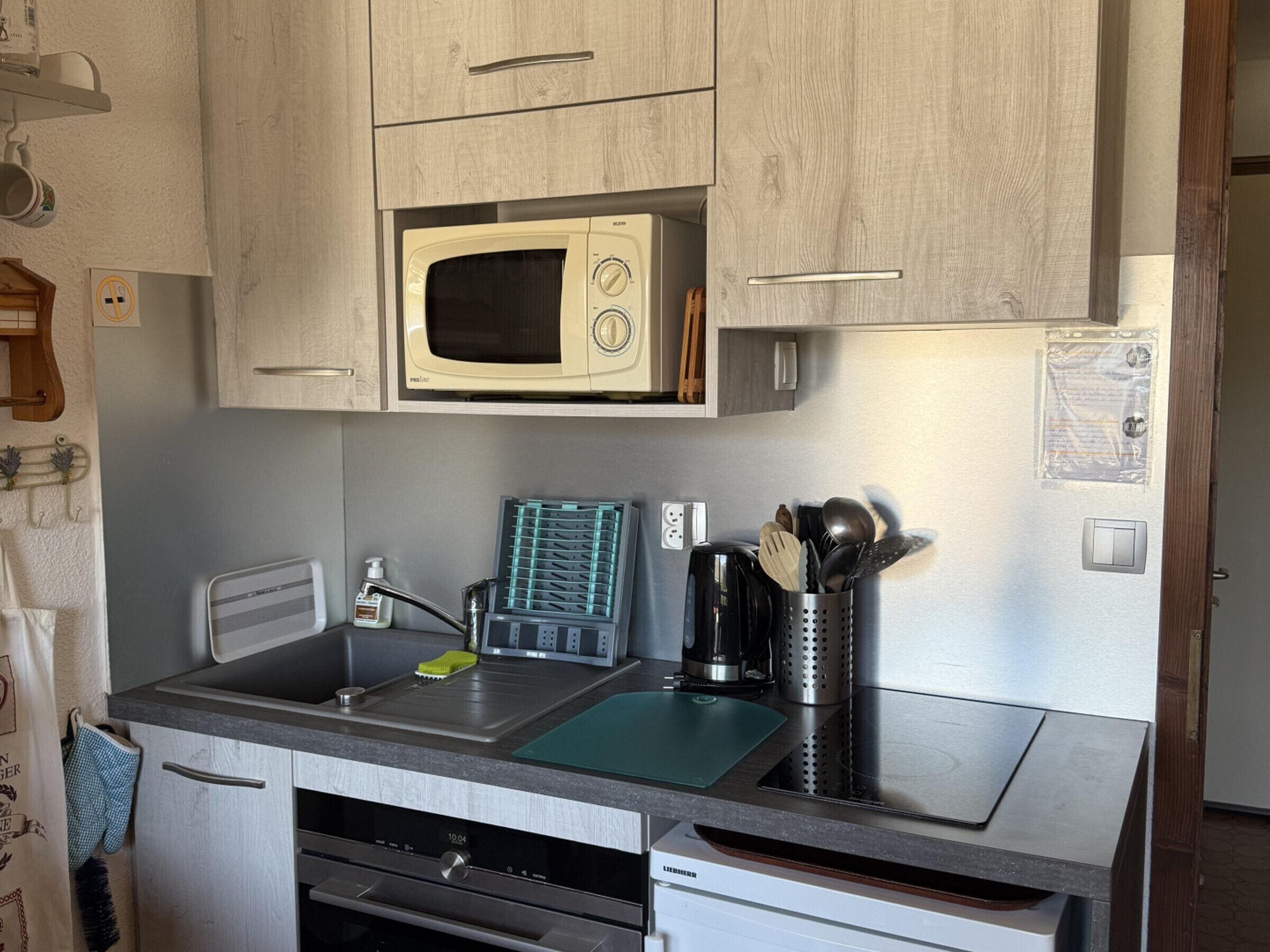 A compact kitchen with a microwave, a coffee maker, and a sink.