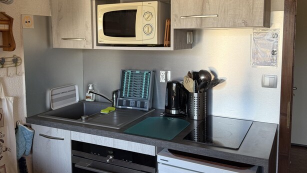 A compact kitchen with a microwave, a coffee maker, and a sink.