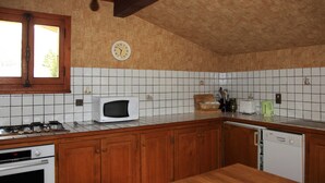 Una cocina con armarios de madera, microondas, estufa y lavavajillas.