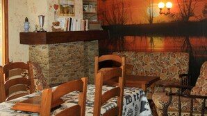 Una habitación acogedora con chimenea, muebles de madera, una estantería y un mural con un atardecer.