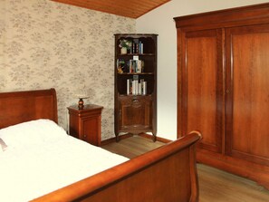 A bedroom with a wooden bed, a nightstand, a wooden bookcase, and a wardrobe.