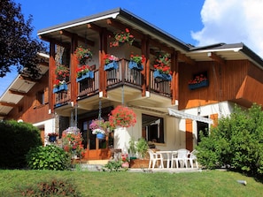 A two-story wooden building with balconies adorned with hanging flower baskets.