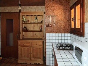 Eine Küche mit Holzschränken, einem Herd und einer gefliesten Spritzschutzwand.