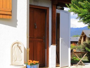 A wooden door with a number plaque, a white wall, and a wooden structure with a roof. - Charming Villa in Samoëns with Wifi and 2 Bedrooms (Samoëns)