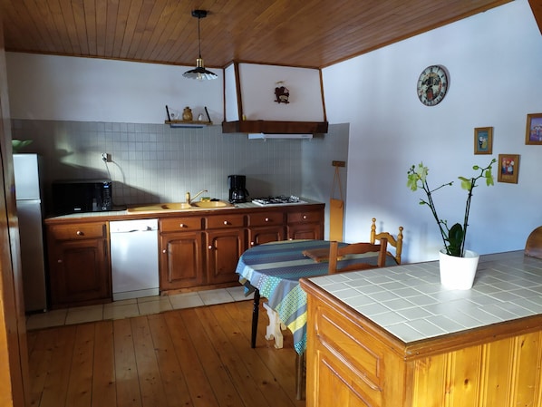 A kitchen with wooden cabinets, a sink, a stove, and a dining area with a table and chairs.