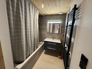 A modern bathroom with a shower, a sink, and a mirror.