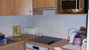 Una cocina con armarios de madera, microondas, cafetera, tostadora y un lavamanos.