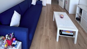 A modern living room with a blue sofa, white coffee table, and a white cabinet. - Bright Blueberry Studio (Bruxelles)