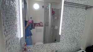 A bathroom with a large mirror, a sink, and a shower area. - Bright Blueberry Studio (Bruxelles)