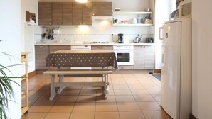 Une cuisine avec des meubles en bois, un réfrigérateur blanc et une table à manger recouverte d’une nappe à pois.