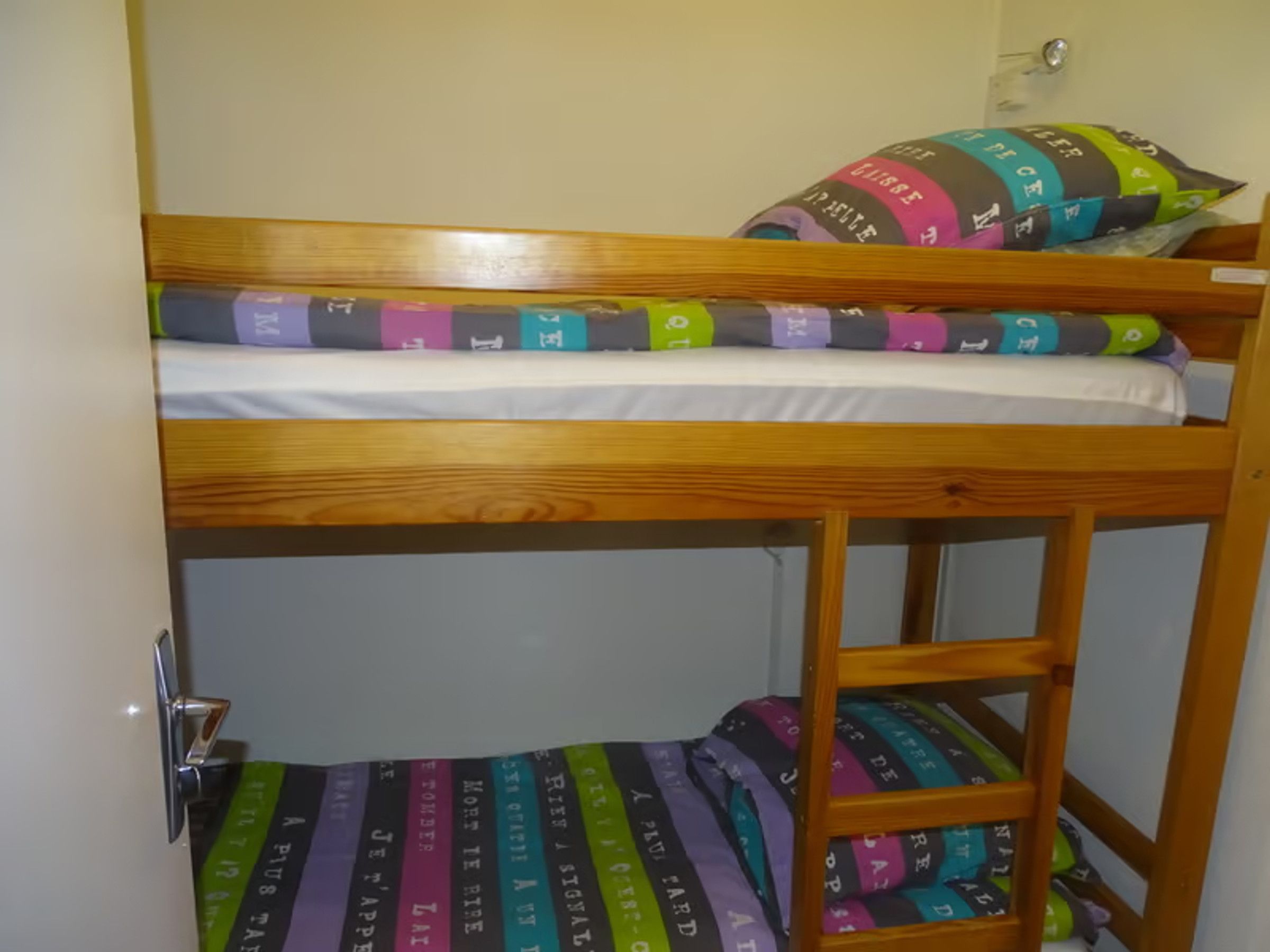 A bunk bed with a lower bunk and a mattress with colorful stripes.
