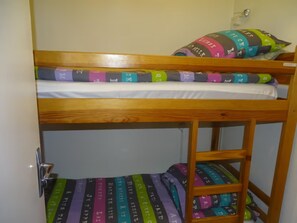 A bunk bed with a lower bunk and a mattress with colorful stripes.
