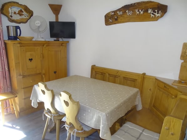 A cozy room with a wooden bed, a table with chairs, a television, and a wall decoration.
