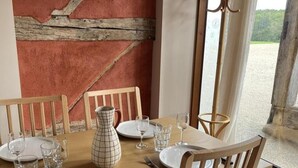 A dining table set with plates, glasses, and a pitcher, with wooden chairs and a view of the outdoors. - Peaceful cottage for 4 guests with garden in Montbeugny (Montbeugny)